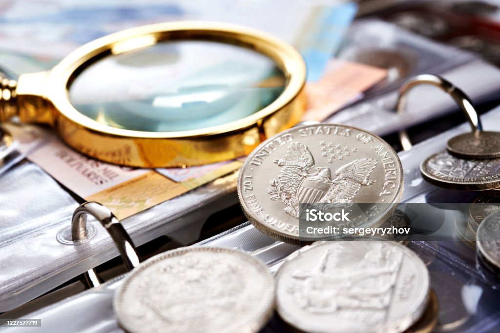 Silver Dollar And Numismatic Coins With Magnifying Glass Stock