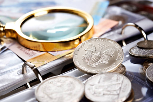 Silver dollar and numismatic coins with magnifying glass Collecting old coins and banknotes. Silver dollar. Numismatics. Old money and notes with magnifying glass coin collection stock pictures, royalty-free photos & images