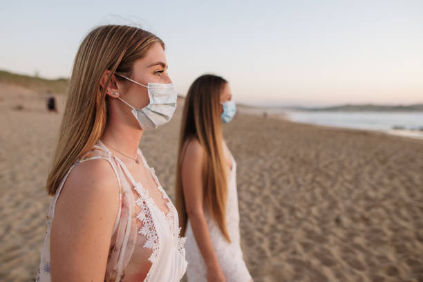 istock Two young women wearing protective face masks at the beach 1227579012
