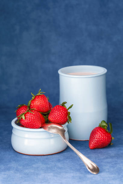 Delicious fresh strawberries in a bowl with yogurt and a spoon stock photo