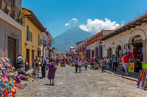 People walking in the main street of Antigua with the Agua volcano in the background.