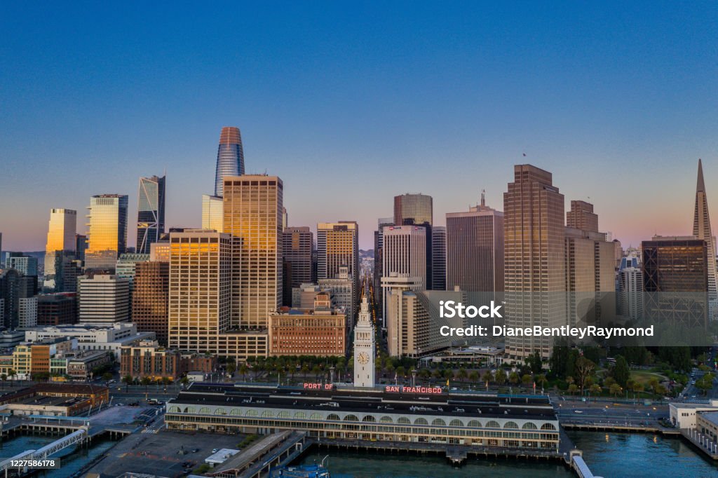 Aerial view of the San Francisco Skyline at Sunrise An aerial view of the San Francisco skyline look over the Ferry Terminal up Market Street. Sunrise light shines off the glass skyscrapers. San Francisco - California Stock Photo