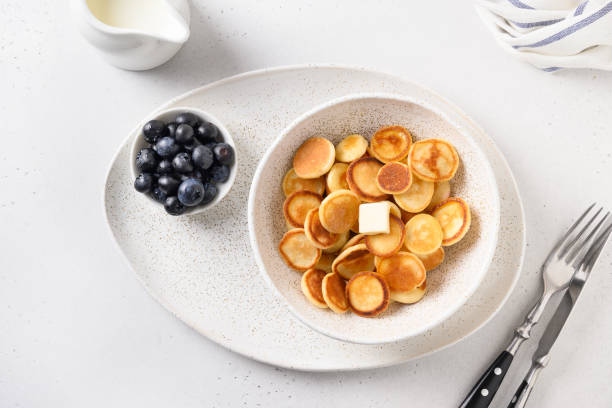 istock Tiny cereal pancakes with blueberry and honey on white background. View from above. 1227586334