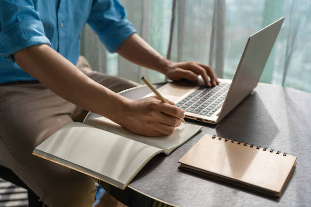 istock Close up hand of Asian man take note for e-learning at home 1227587907