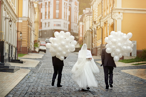 The bride and friends go into the distance with a huge number of balloons