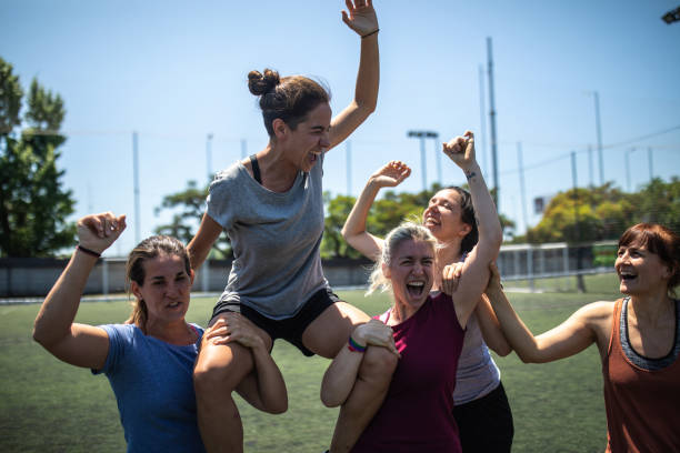 Excited teammates celebrating the victory after soccer match Female soccer players celebrating victory after soccer game, carrying player of the game on shoulders and cheering together most valuable player stock pictures, royalty-free photos & images
