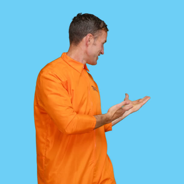 istock Presenter standing in front of blue background wearing jumpsuit 1227588312
