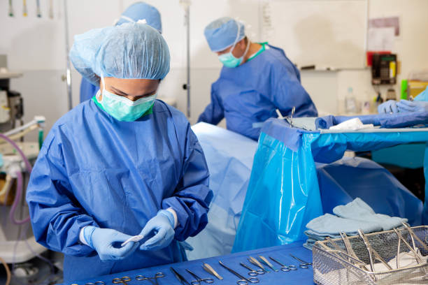 enfermera quirúrgica prepara instrumentos para cirujanos - hair net nurse scrubs asian ethnicity fotografías e imágenes de stock