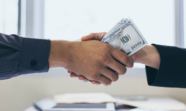 istock Shaking hands with congratulations on an evil plan, Businessmen give dollars to bribe employees in signing contracts to buy illegal land and real estate, corruption and Bribery concept, 1227589466