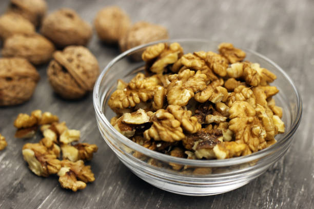 istock Walnut kernels in a bowl and whole nuts on an old gray table 1227591004