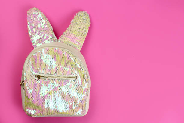 istock Shiny child's backpack with the rabbit ears with sequins on a pink background, copy space 1227591215