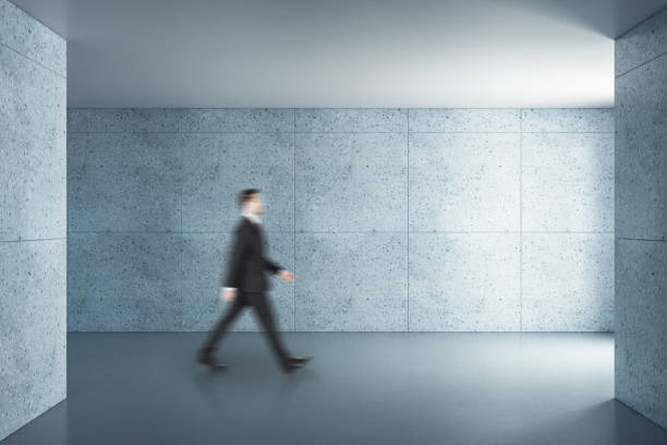 istock Businessman walking in concrete interior 1227591943