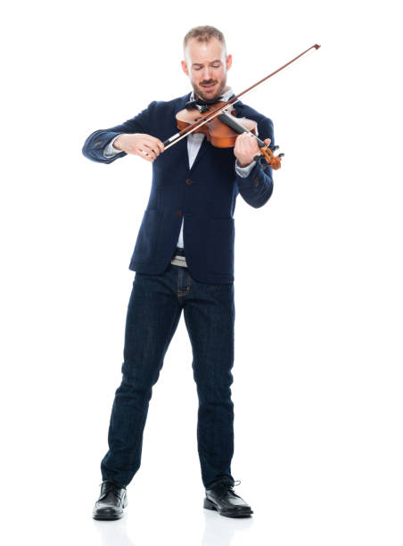 músico masculino caucásico de pie frente a fondo blanco usando ropa de negocios y sosteniendo instrumento musical - violinista fotografías e imágenes de stock