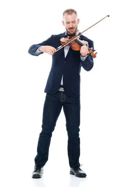 Photo of Caucasian male musician standing in front of white background wearing businesswear and holding musical instrument