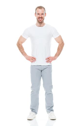 Front view of aged 30-39 years old with brown hair caucasian young male standing in front of white background wearing canvas shoe who is successful with hand on hip