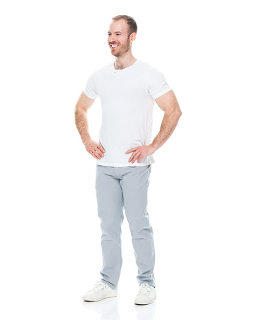 Side view of aged 30-39 years old with short hair caucasian male standing in front of white background wearing t-shirt who is laughing with hand on hip