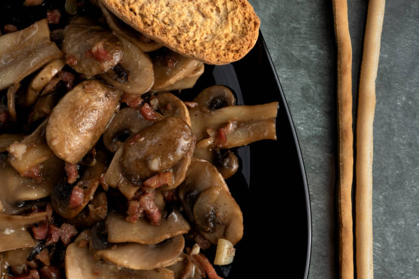 istock Cooked mushrroms with ham pieces on a black plate 1227593476