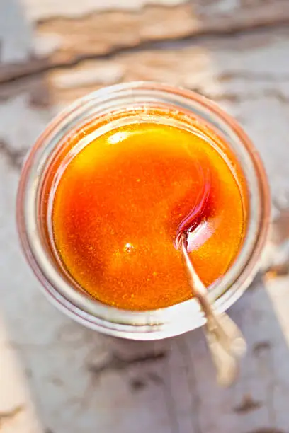 Photo of Manuka honey in the jar with spoon, morning sunlight