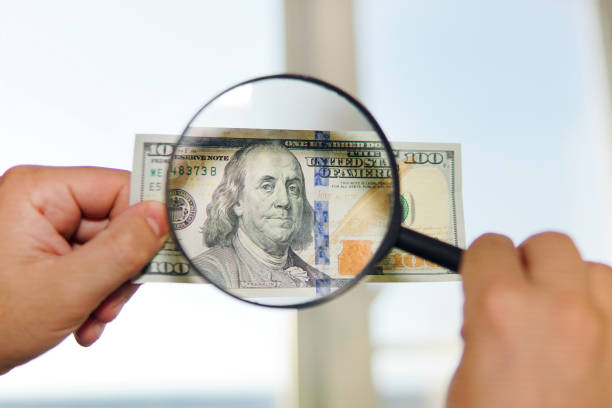 istock two dollar bill and magnifying glass isolated on white 1227594873