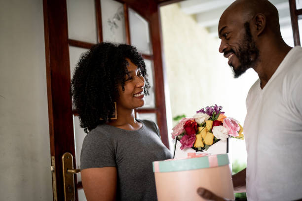 marito sorprende la moglie con un fiore e presente a casa - men african descent giving flower foto e immagini stock