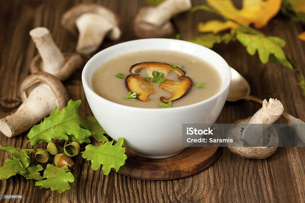 A white bowl of mushroom soup on a wooden counter Bowl of cream of mushroom soup with fried mushrooms Cream Soup Stock Photo