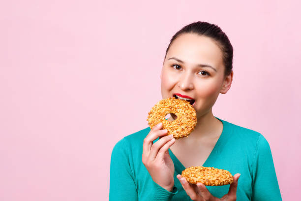 istock a young smiling woman with sweets in her hands on a pink background. 1227599014