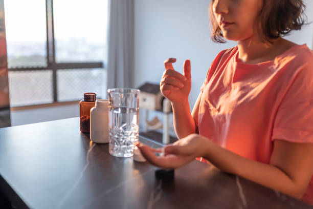 femme prenant des suppléments à la maison - vitamin pill flash photos et images de collection