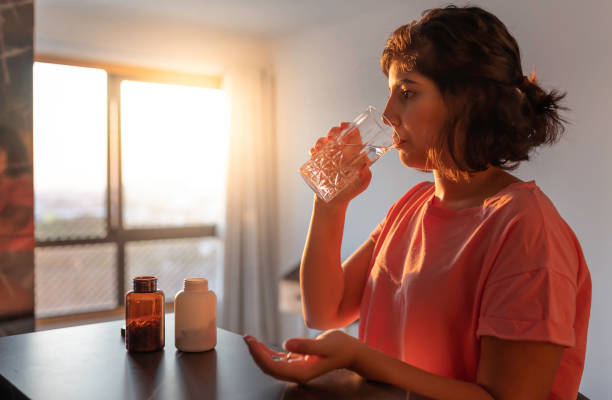 woman taking supplements at home Shot of a young woman taking supplements at home nutritional supplement photos stock pictures, royalty-free photos & images