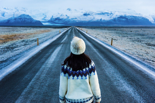 Female traveler standing on a scenic road in Iceland