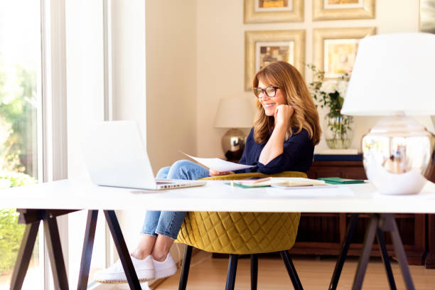 istock Attractive mature woman sitting at desk and using laptop while working at home 1227601219