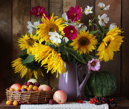 still life with sunflowers, apples and plums. a bouquet of garden flowers, berries, vegetables and fruits.