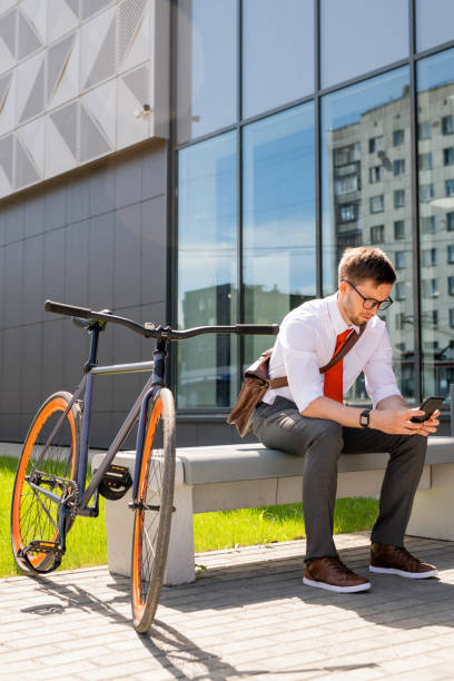 istock Young businessman scrolling in smartphone on bench on sunny summer day 1227607200