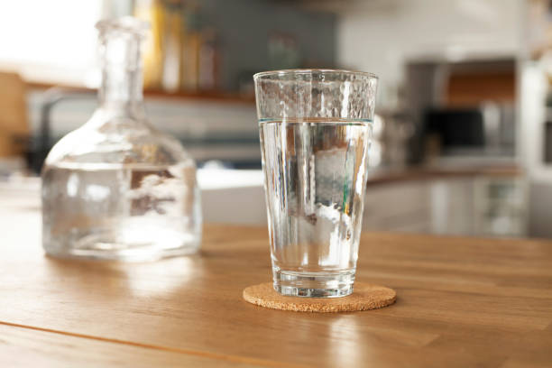 copo de água pura e garrafa na mesa da cozinha - water bottle purified water water drink - fotografias e filmes do acervo