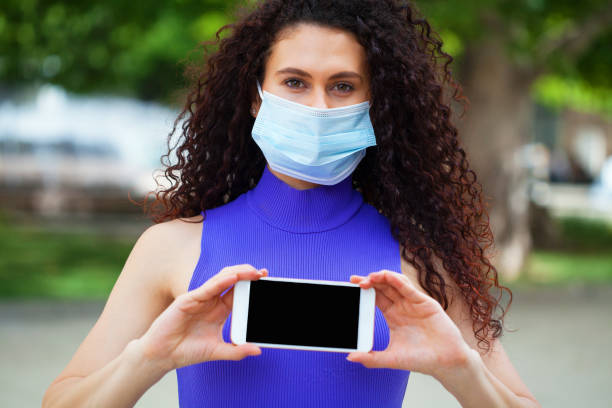 istock Young woman with a protective face mask using smart phone 1227607622