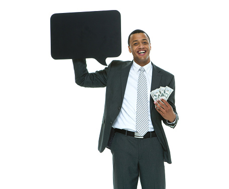 Portrait of african-american ethnicity young male businessman standing in front of white background wearing businesswear who is contemplating and holding speech bubble with copy space