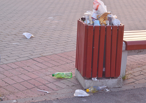 Overflowing trash can on stone pavement background.The plastic pollution