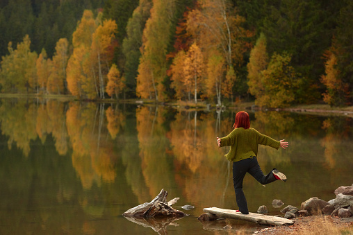 Redhead woman jumping and feeling free in the forest
