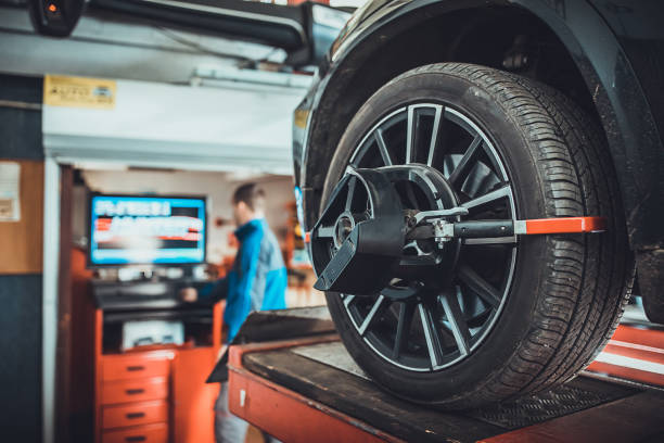 Wheel alignment equipment on a car wheel in a repair station One man, mechanic in auto repair shop, wheel alignment equipment on a car wheel in a repair station. car boot stock pictures, royalty-free photos & images