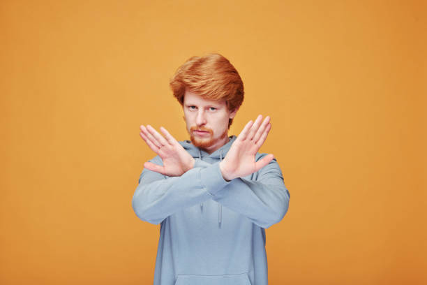 istock Young bearded man crossing his hands in front of himself in isolation 1227610075