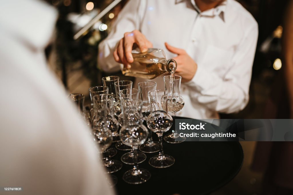 photo of a waiter seving alcohol in glasses a waiter seving alcohol in glasses Alcohol - Drink Stock Photo