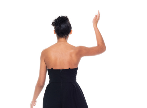 Rear view of aged 20-29 years old who is beautiful african ethnicity female in front of white background wearing dress who is showing cool attitude and greeting and showing waving gesture