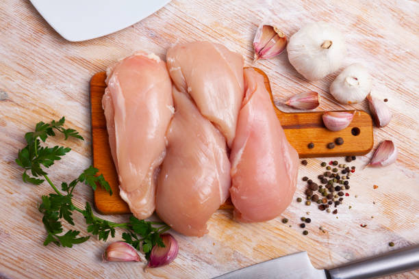 preparation of raw chicken breast fillet with parsley and garlic on cutting board - garlic chicken breast raw chicken imagens e fotografias de stock