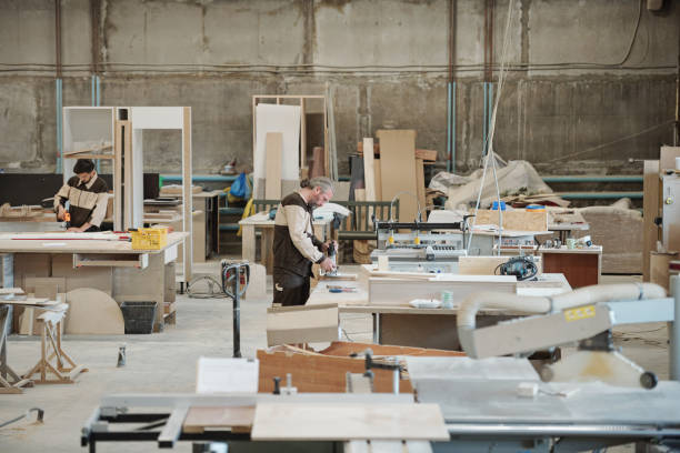 istock Two workers standing by workbenches in workshop and drilling wooden workpieces 1227614070