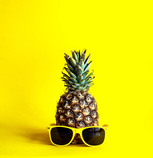 istock Pineapple on a bright yellow background with yellow glasses 1227614935