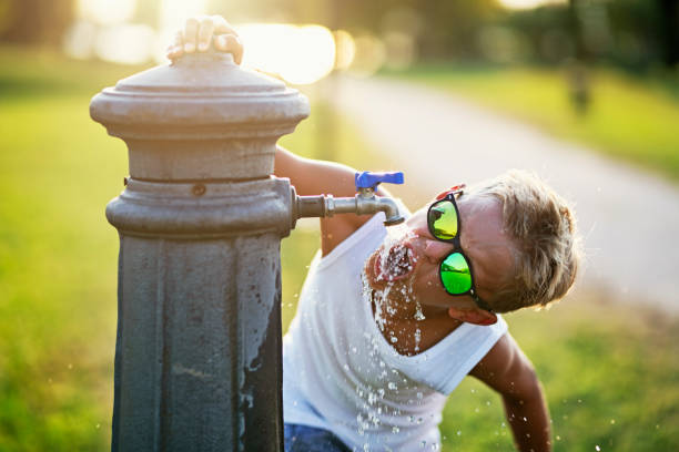 Very thirsty boy drinking water from public fountain.Nikon D850