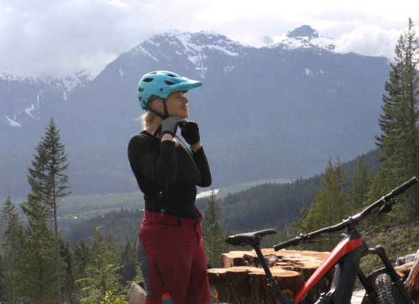 istock Female e-mountain biker arrives on a promontory above a valley, forest and mountains 1227617992