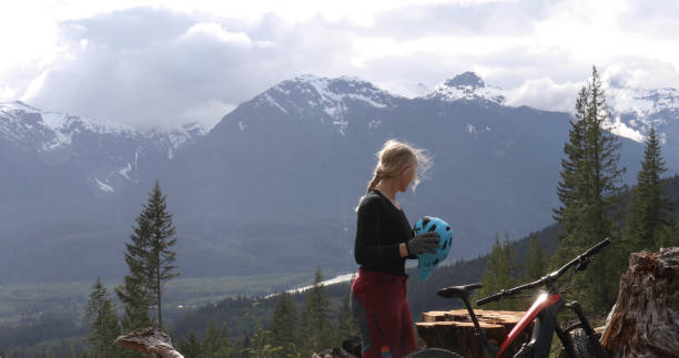 istock Female e-mountain biker arrives on a promontory above a valley, forest and mountains 1227618567
