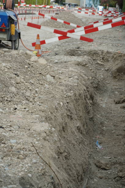 istock Road construction site, civil engineering construction site, holes in the ground for pipes. The site is provided with barrier planks in red and white for security reasons. 1227619035