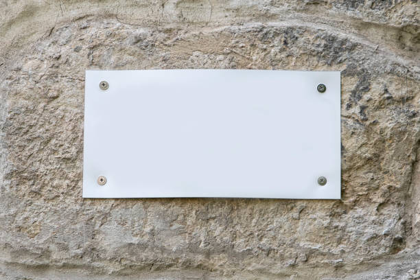 istock A white blank sign is screwed to the stone wall. For text and copy space. 1227619995