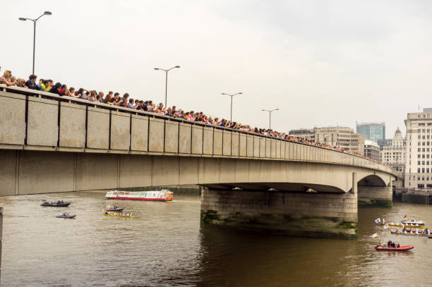 menschenmassen auf der london bridge beobachten flussprozession - olympic torch stock-fotos und bilder
